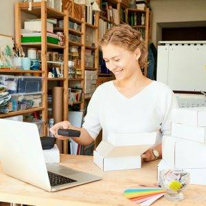 Happy owner of local business. Female entrepreneur collecting and packing gifts